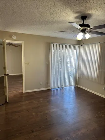a view of an empty room with a ceiling fan and wooden floor