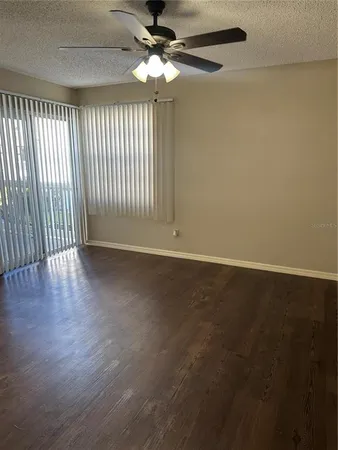 an empty room with wooden floor fan and windows