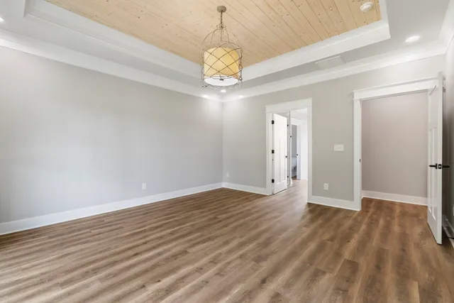 a view of an empty room with chandelier and wooden floor