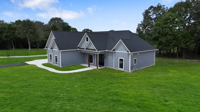 a view of a house with a big yard potted plants and large tree