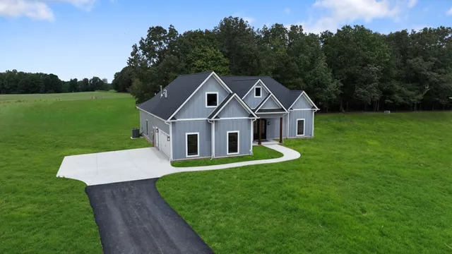 a front view of a house with a yard and trees