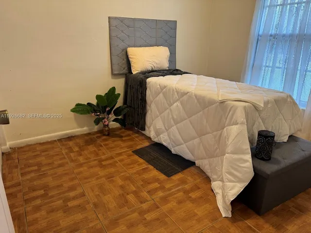 a bedroom with a bed and a lamp on dresser