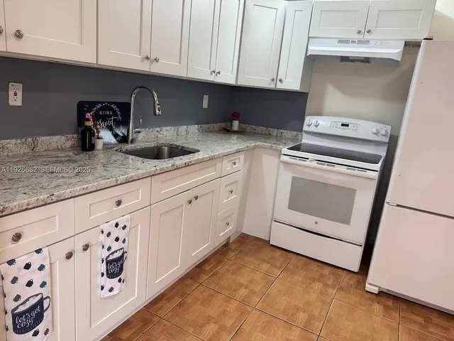 a kitchen with granite countertop white cabinets and white appliances