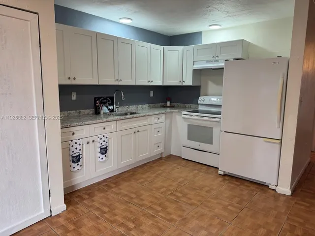 a kitchen with white cabinets and white appliances