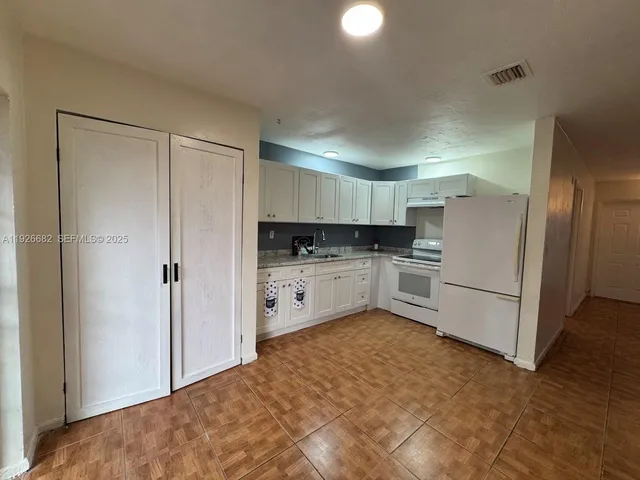 a kitchen with white cabinets and white appliances