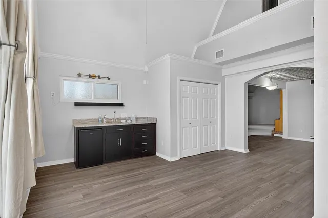 a view of kitchen and empty room with wooden floor
