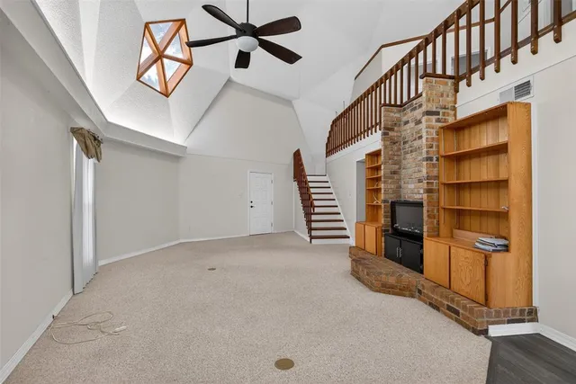 a view of an empty room with stairs and a window