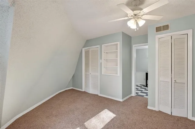 an empty room with closet and a ceiling fan