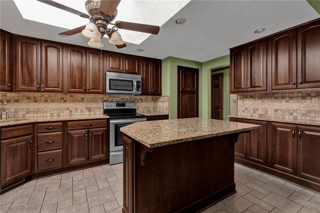 4930 Dutch Ridge Road Brighton Township, PA 15009 - Photo 12 of 25 a kitchen with kitchen island granite countertop wooden cabinets a stove top oven a granite counter top and a window