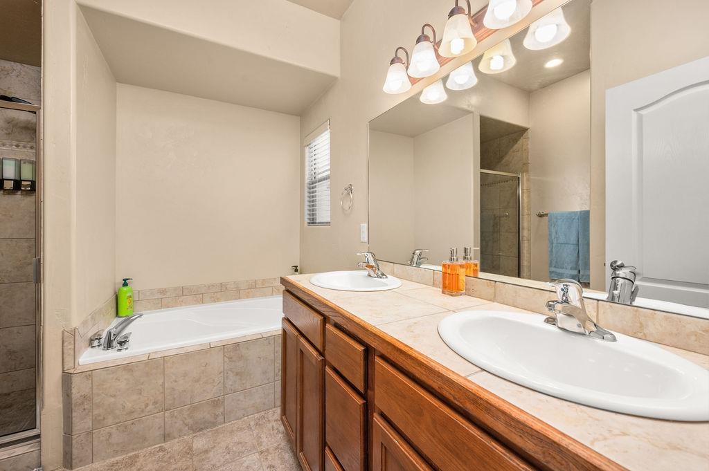 2436 1/2 Jack Creek Road Grand Junction, CO 81505 - Photo 17 of 36 a bathroom with a granite countertop sink a bathtub a mirror and a shower