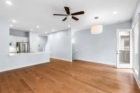 a view of kitchen and empty room with wooden floor