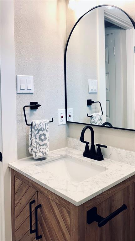 4603 Junius Street, Unit 8 Dallas, TX 75246 - Photo 10 of 16 Bathroom featuring vanity, arched mirror, contemporary lighting, and designer touches.