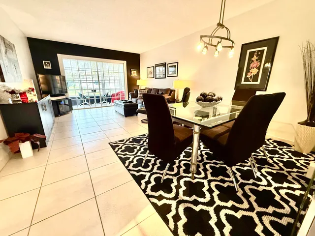 a living room with couches a flat screen tv and a dining table with garden view