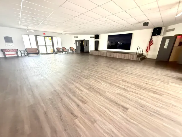 a view of an empty room with wooden floor and windows