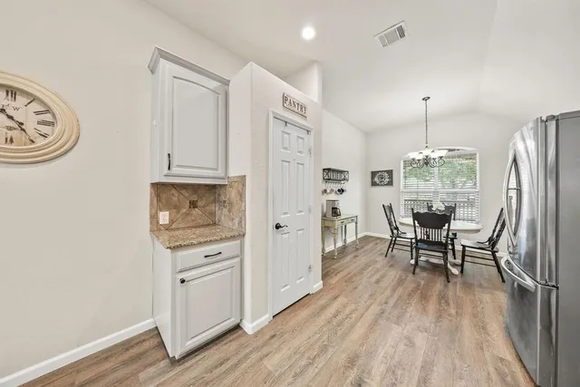 a kitchen with stainless steel appliances a dining table chairs and wooden floor