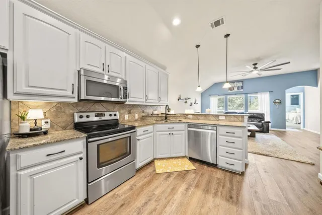 a kitchen with granite countertop white cabinets stainless steel appliances and a sink