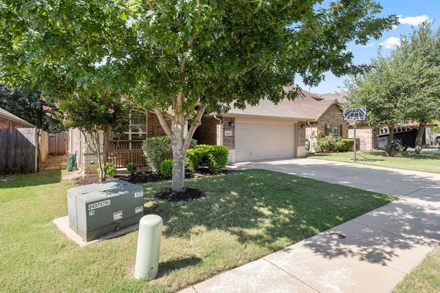 a front view of a house with garden and trees