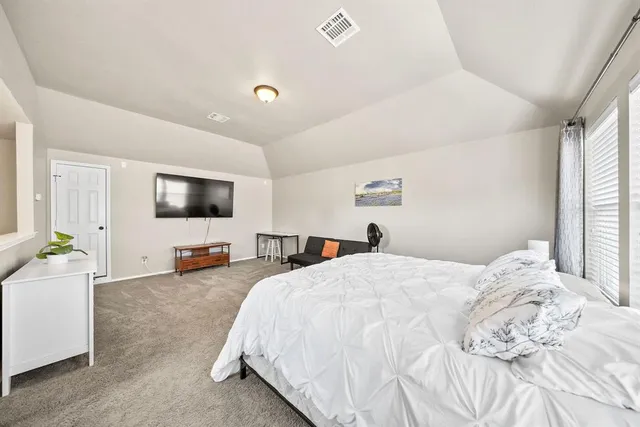a spacious bedroom with a bed and a flat screen tv