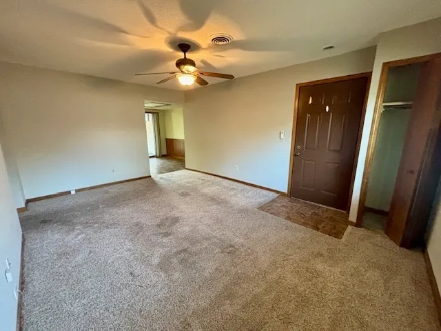 an empty room with closet and a chandelier fan