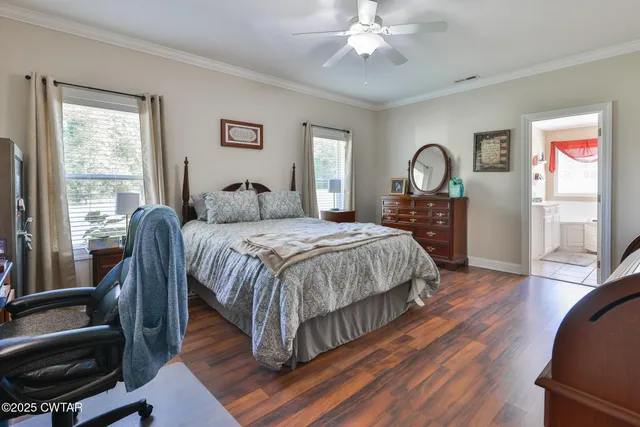 a bedroom with a large bed a chandelier and windows