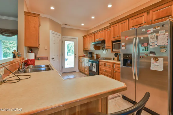 a kitchen with stainless steel appliances granite countertop a stove a refrigerator a oven a sink with island chairs and wooden cabinets