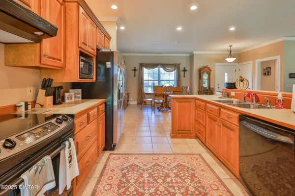 a kitchen with stainless steel appliances granite countertop a stove a sink dishwasher and a refrigerator with wooden floor