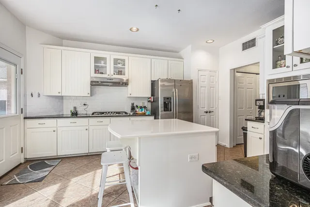 a kitchen with stainless steel appliances granite countertop a sink stove refrigerator and white cabinets with wooden floor