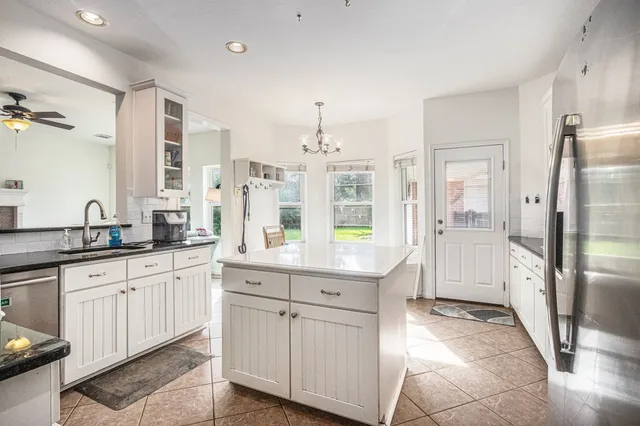 a large white kitchen with granite countertop a sink and stainless steel appliances