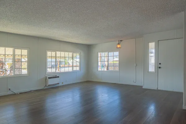 an empty room with wooden floor and windows
