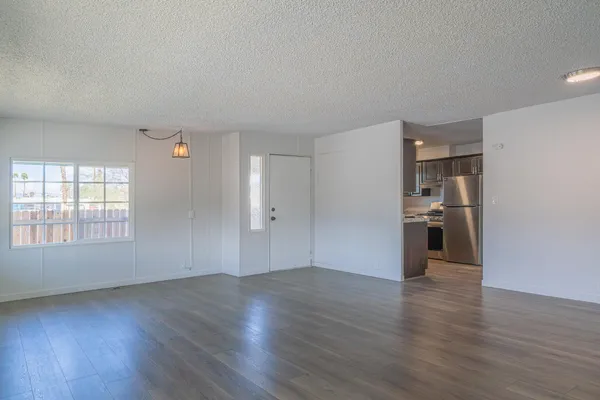 an empty room with wooden floor and windows