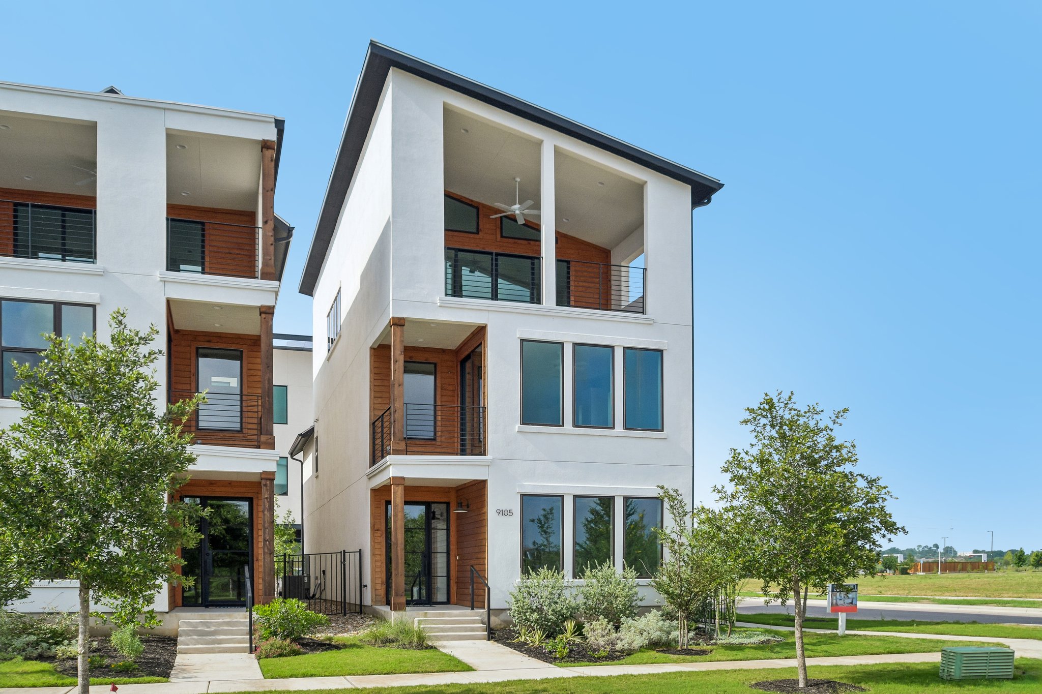 Bold modern architecture defines this vertical dwelling, featuring multiple balconies and rich wood accents against a crisp white facade.