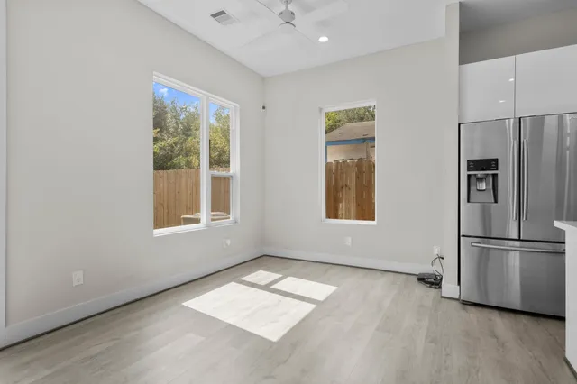 an empty room with wooden floor and windows