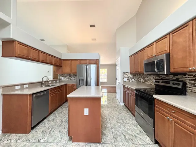 a large kitchen with stainless steel appliances granite countertop a stove top oven a sink dishwasher a dining table and chairs with wooden floor