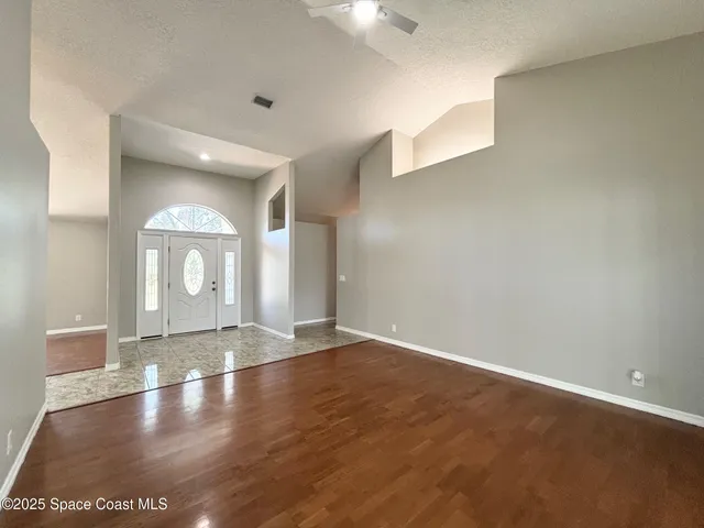 a view of an empty room with window and wooden floor