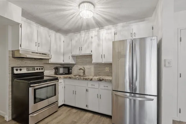 a kitchen with stainless steel appliances white cabinets and a refrigerator