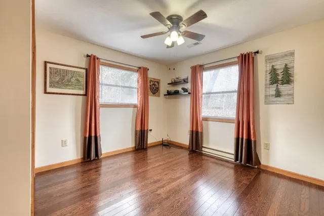 a view of an empty room with a window and wooden floor