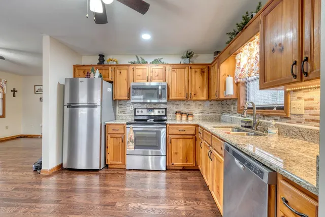 a kitchen with stainless steel appliances granite countertop a refrigerator a stove a sink and a microwave
