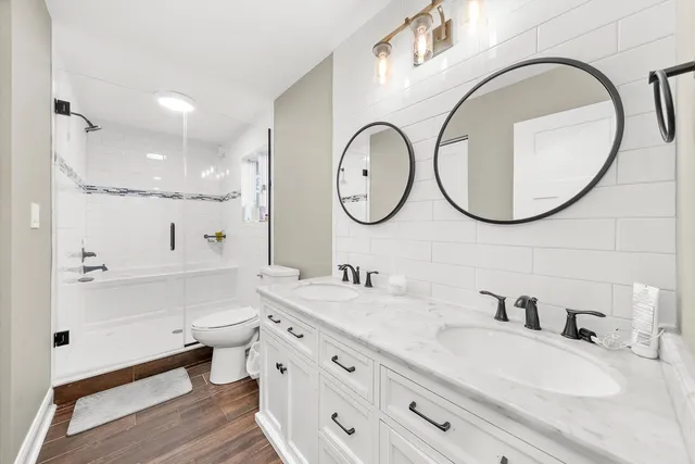 a bathroom with a double vanity sink mirror and a toilet