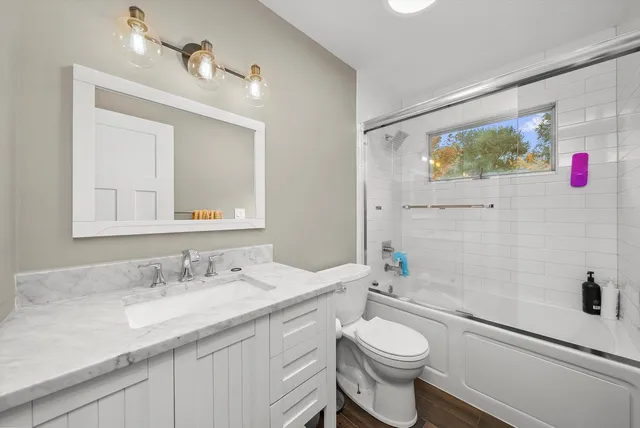 a bathroom with a granite countertop toilet sink and mirror