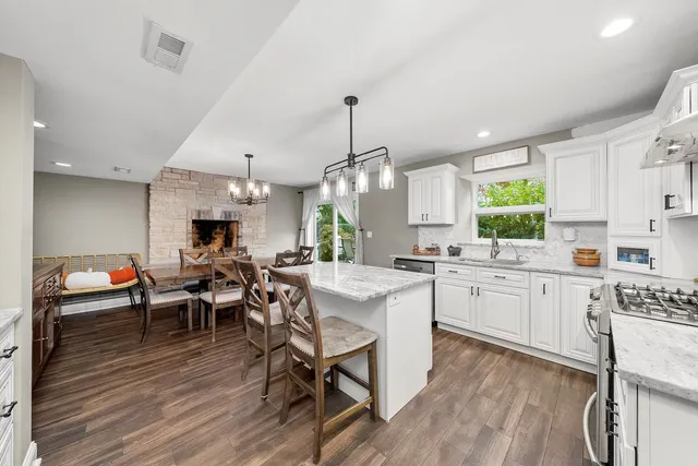 a kitchen with stainless steel appliances a dining table chairs stove and wooden floor
