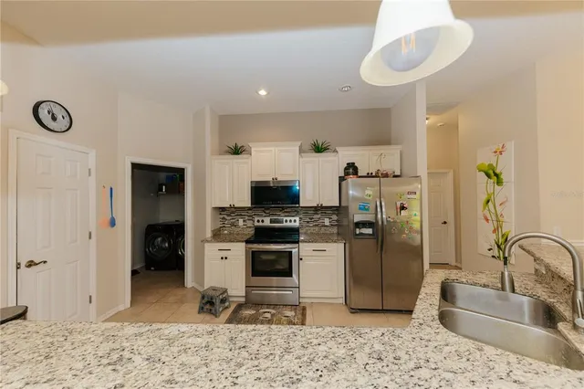 a kitchen with stainless steel appliances granite countertop a refrigerator a stove and a sink