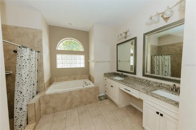 a bathroom with a granite countertop tub a sink and a large mirror