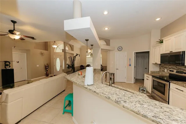 a large kitchen with stainless steel appliances a large counter top a stove and a refrigerator