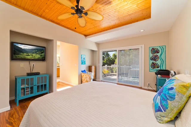 a bedroom with a bed and a flat tv screen on dresser