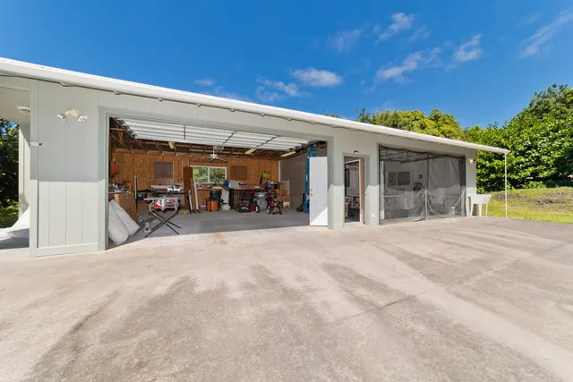 a view of a house with a barbeque and large trees