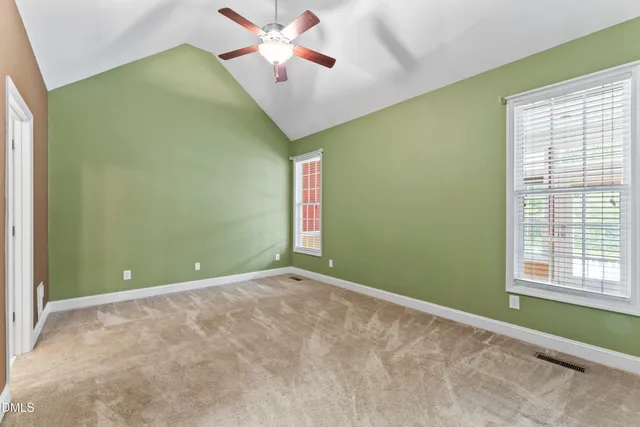 a view of an empty room with a window and a chandelier fan