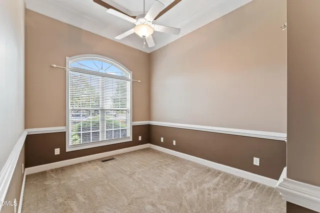 an empty room with chandelier fan and windows