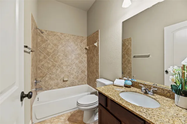 a bathroom with a granite countertop sink a toilet a mirror a bathtub and shower