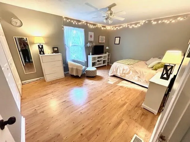 a spacious bedroom with a bed and a flat tv screen on dresser