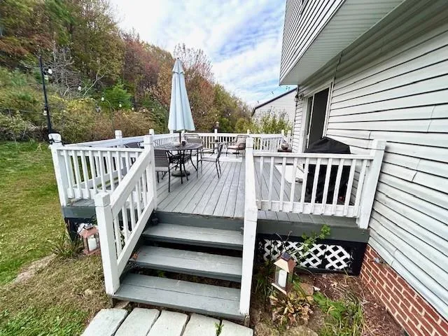 a view of balcony with wooden floor outdoor seating and yard in the back